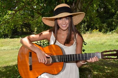 Portrait of beautiful woman playing guitar on field
