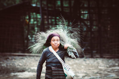 Mature woman carrying plant while walking against building