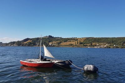 Boat in sea against clear blue sky