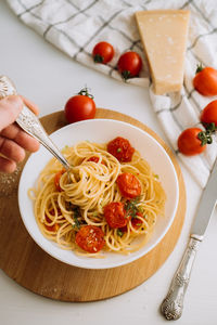 Portion of spaghetti pasta with parmesan and cherry tomatoes sprinkled with spices in a plate
