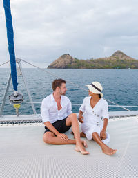 Full length of woman sitting on sea against sky