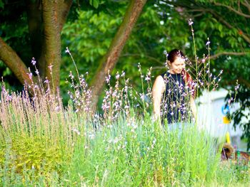 Woman standing on grass against trees