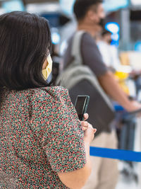 Rear view of woman using mobile phone outdoors