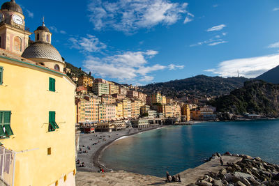 Buildings by sea against sky