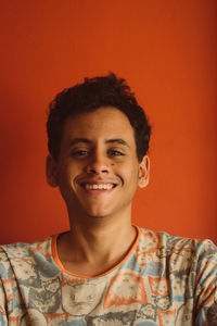 Portrait of smiling young woman against orange background