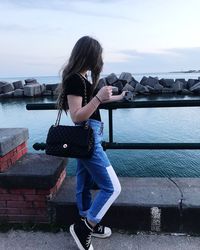 Rear view of woman standing by railing against sea