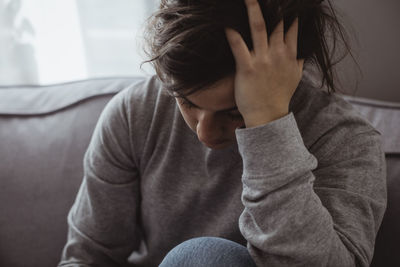 Close-up of sad woman having headache while sitting at home