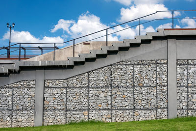 Metallic structure by wall against sky