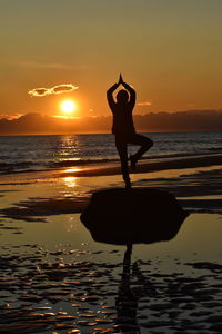 Silhouette man standing on beach against sky during sunset