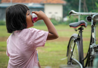 Side view of girl photographing with bicycle