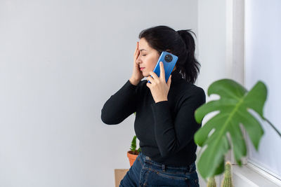 Tired girl talking on the phone with her eyes closed and gets bad news