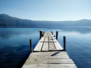 Pier over lake against clear sky