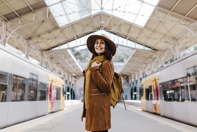 Portrait of smiling woman standing at railroad station