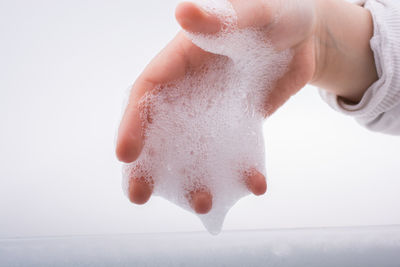 Close-up of hand being washed against white background