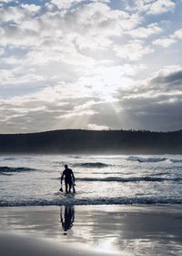 Silhouette man walking at beach against sky during sunset