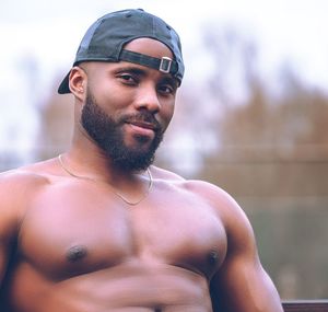 Portrait of shirtless man standing against wall