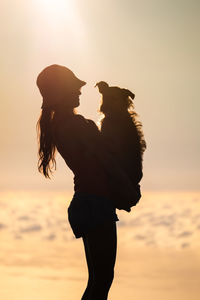 Side view of couple standing against sky during sunset