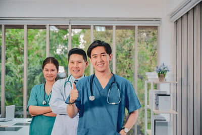 Portrait of smiling doctors gesturing while standing at hospital