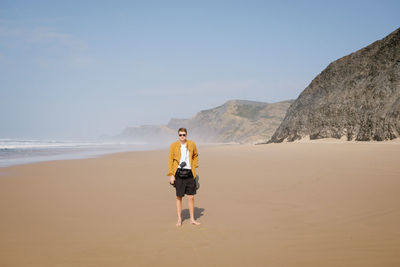 Rear view of man walking on beach against clear sky