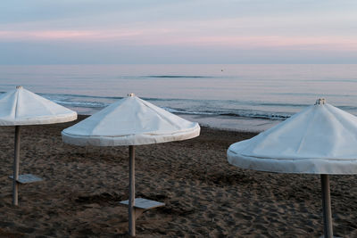 Tent on beach against sky during sunset