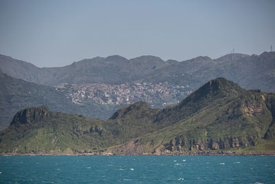 Scenic view of sea by mountains against sky