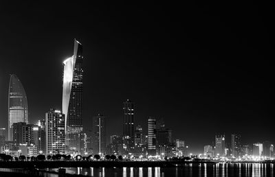 Illuminated buildings in city against sky at night