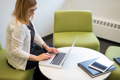 Rear view of woman using laptop on table