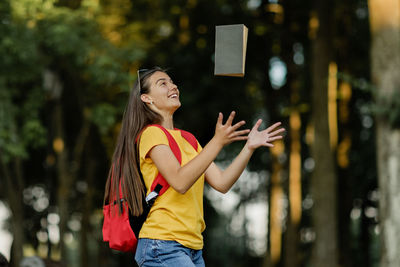 A cheerful girl throws up a book, rejoices at the successful passing of exams