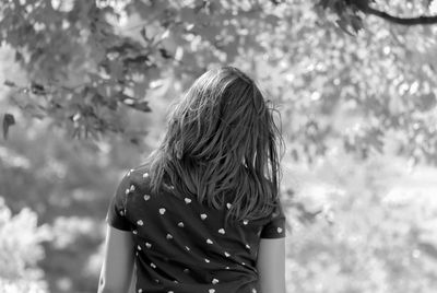 Rear view of woman standing against trees