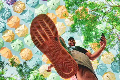 Low angle portrait of young man against tree