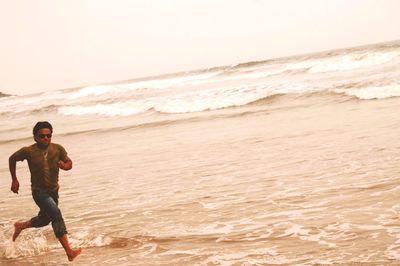 Full length of man running on shore at beach