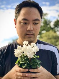 Portrait of young man holding flowering plant