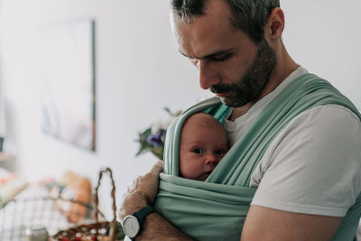 Portrait of father carrying son in baby sling or baby wrap