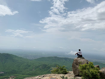 Man sitting on rock against sky looking at the city of junagadh, gujarat, india.