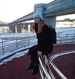 Woman standing on railing during winter