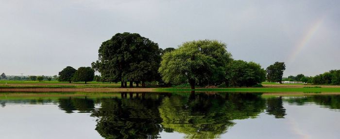 Panoramic view of lake and field against sky