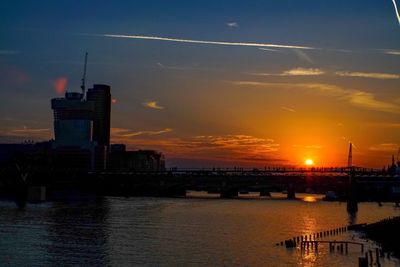 Silhouette of city at waterfront during sunset