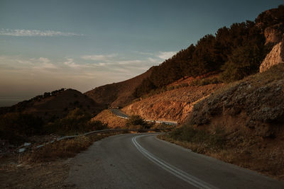 Empty road along landscape and mountains against sky