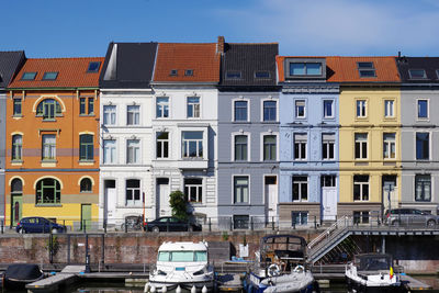 Residential buildings by canal against sky in city