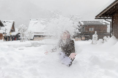 People on snow covered building during winter