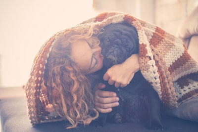 Mature woman kissing dog on bed at home