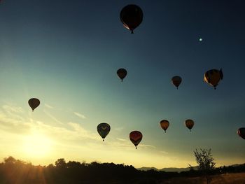 Low angle view of hot air balloons flying against sky during sunset