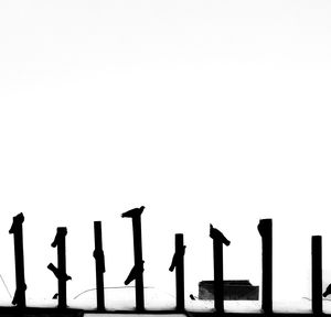 Silhouette of poles against clear sky