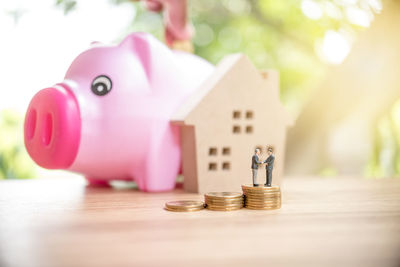 Close-up of figurines with coins and model house on wooden table