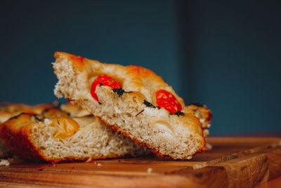 Homemade italian focaccia slices, with tomato and olive oil on a rustic wooden background.