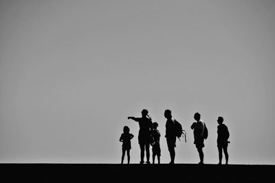 Silhouette of people standing against sky during sunset