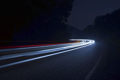 Light trails on road against sky at night