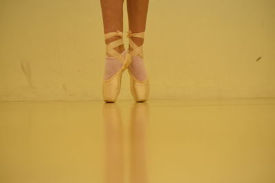 Low section of ballet dancer tiptoeing on floor