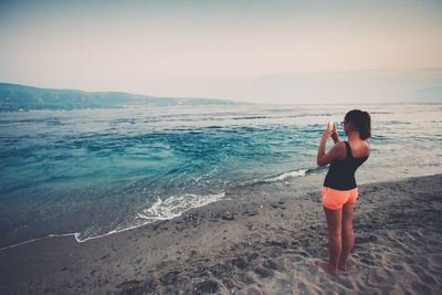 Full length of man photographing on beach