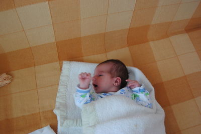 Close-up of cute baby lying on bed at home